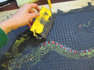 Spreading the grout over the surface of the mosaic